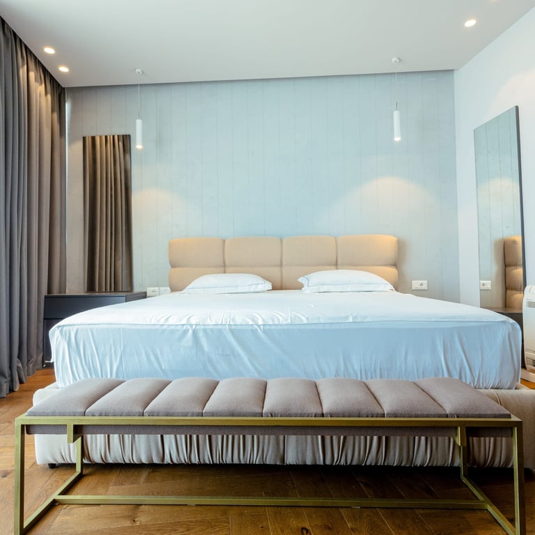 Modern bedroom with king-size bed, beige headboard, and soft blue accent wall