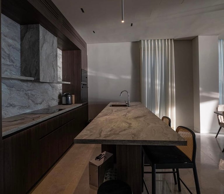 Modern kitchen with dark cabinetry, marble backsplash, wooden island with sink, and floor-to-ceiling white curtains