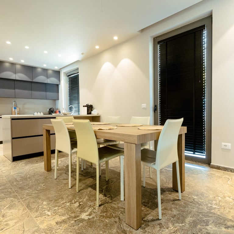 Modern dining room with wooden table, cream chairs, and open kitchen