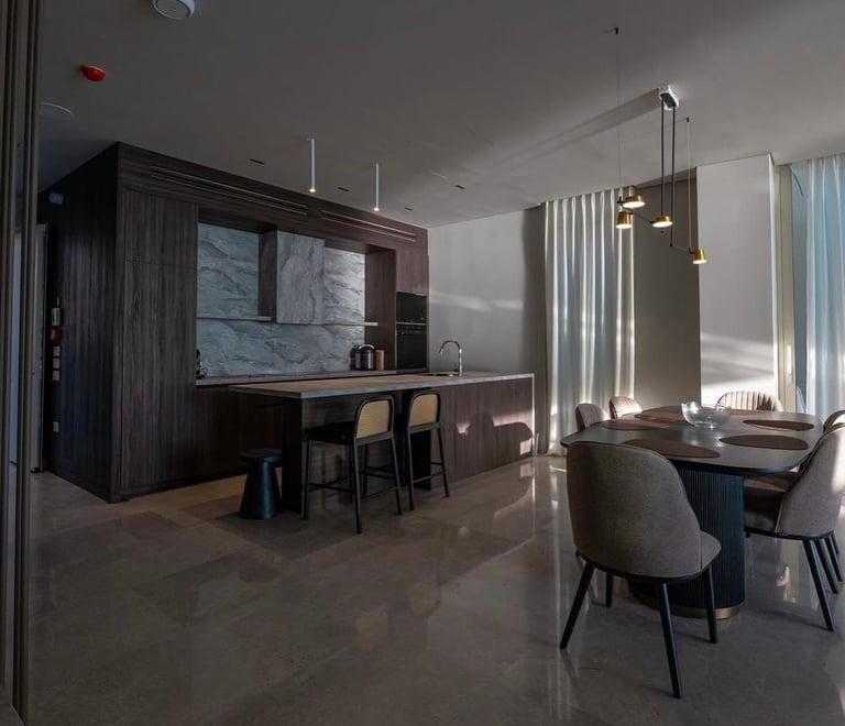 Modern open-concept kitchen and dining area with dark wood cabinetry, marble backsplash, bar seating, and contemporary furniture near large windows