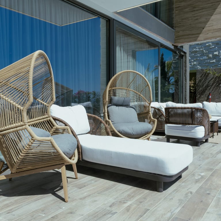 Modern rooftop terrace with woven hanging chairs and sun loungers at dusk
