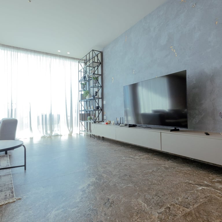Modern living room with flat-screen TV, bright windows, and polished concrete flooring