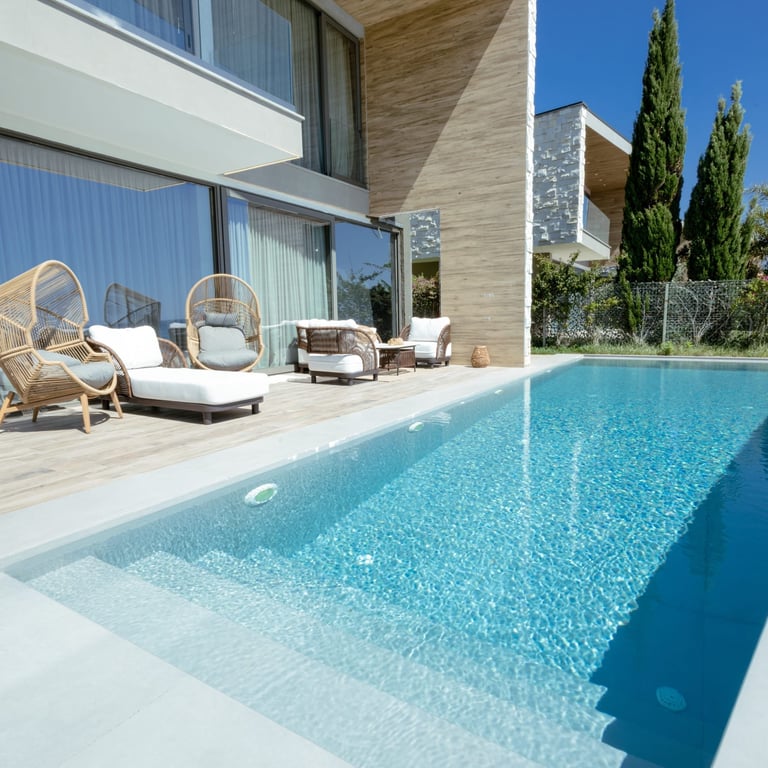 Modern luxury home with rectangular swimming pool, lounge chairs, and contemporary architecture