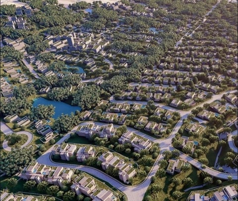 Aerial view of a planned residential community with winding streets, multi-family buildings, waterways, and surrounding green spaces