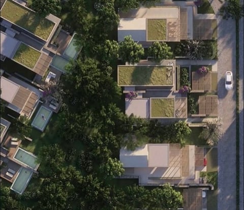 Aerial view of residential buildings with rooftop gardens and green spaces surrounded by trees and streets