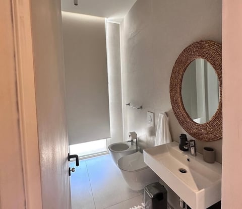 Modern bathroom with white vanity, double sinks, round mirror, and minimalist decor
