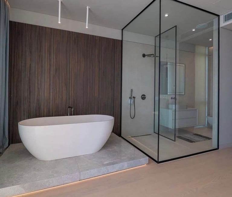 Modern bathroom with white freestanding tub and glass-enclosed shower with black framing, wood accent wall, and concrete flooring